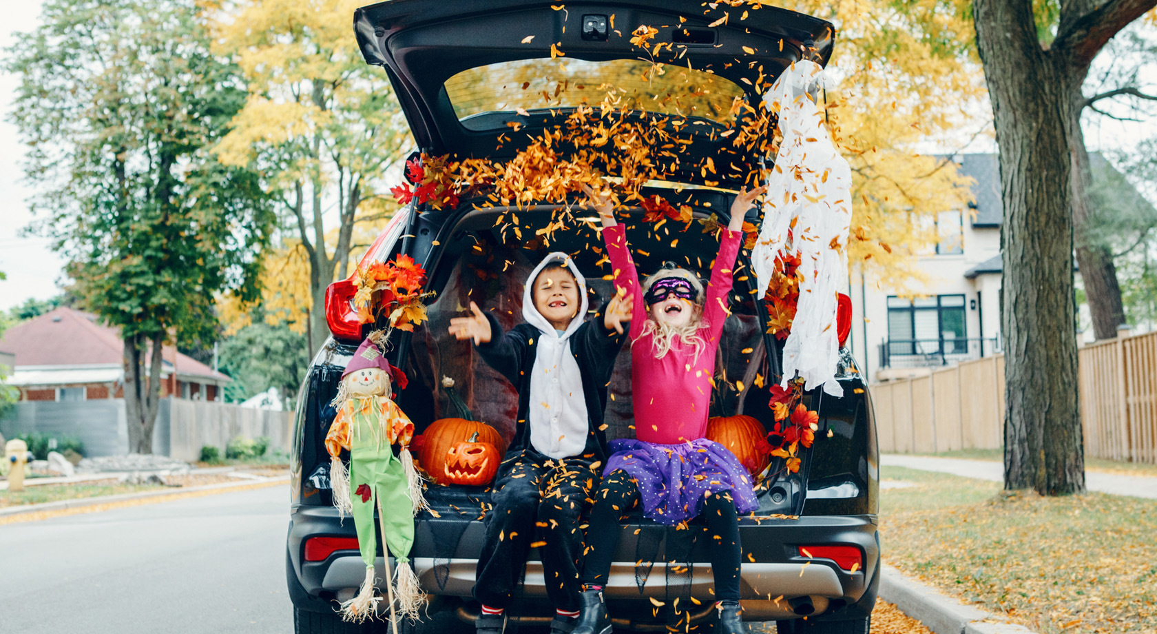 Young boy and girl in costumes sitting in back of a car